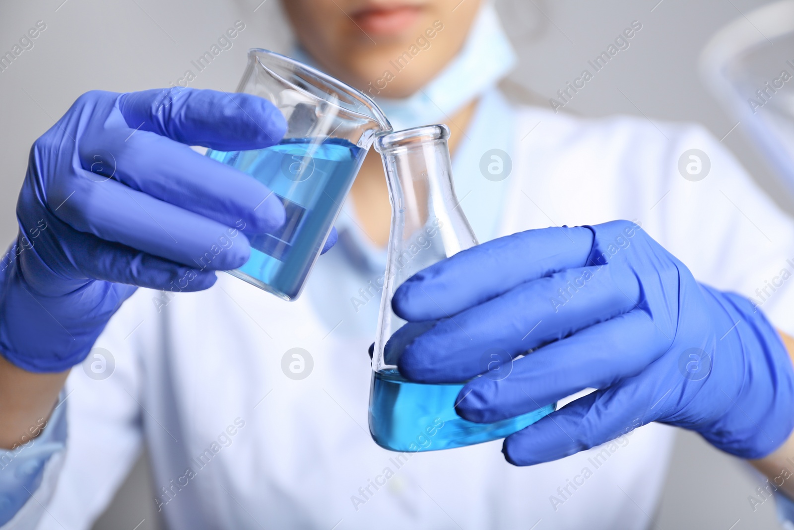 Photo of Doctor pouring blue liquid into flask, closeup. Laboratory analysis