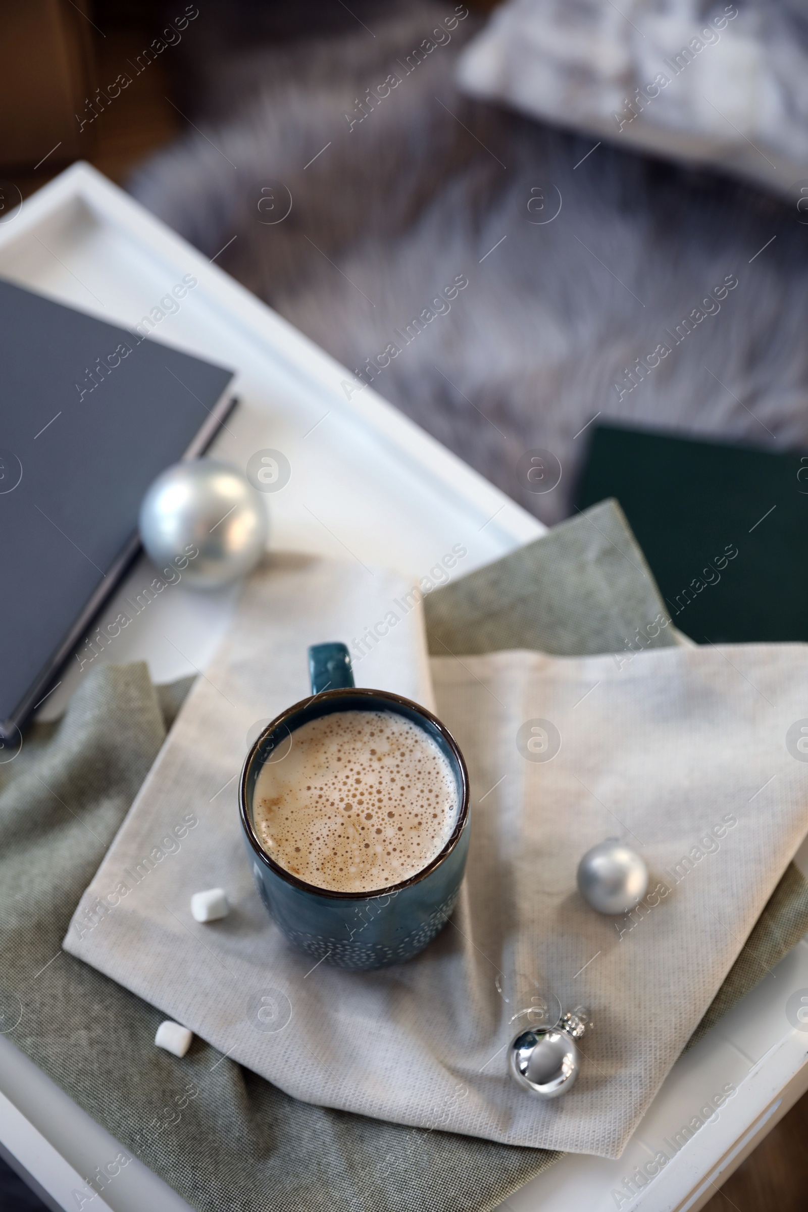 Photo of Cup of cocoa, book and balls on tray at home, above view. Christmas celebration