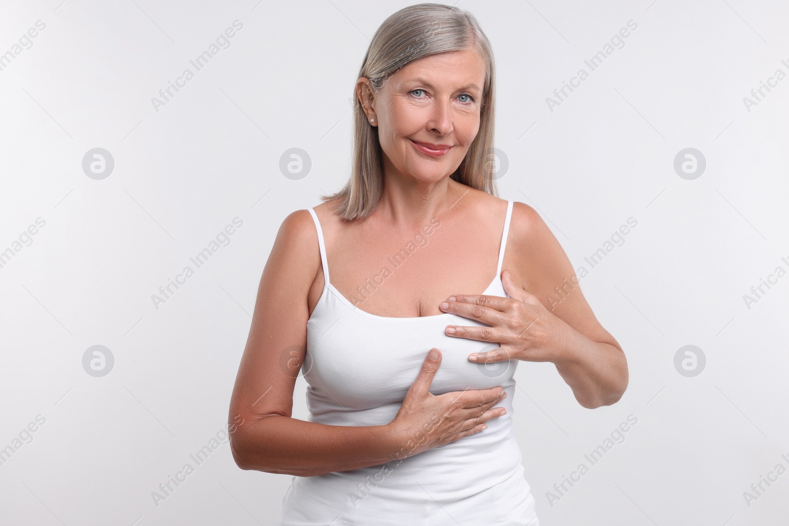 Photo of Beautiful senior woman doing breast self-examination on white background