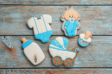 Cute tasty cookies of different shapes on light blue wooden table, flat lay. Baby shower party