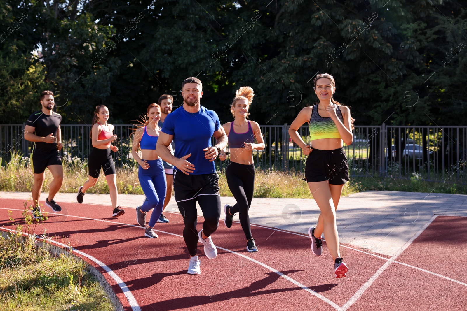 Photo of Group of people running at stadium on sunny day