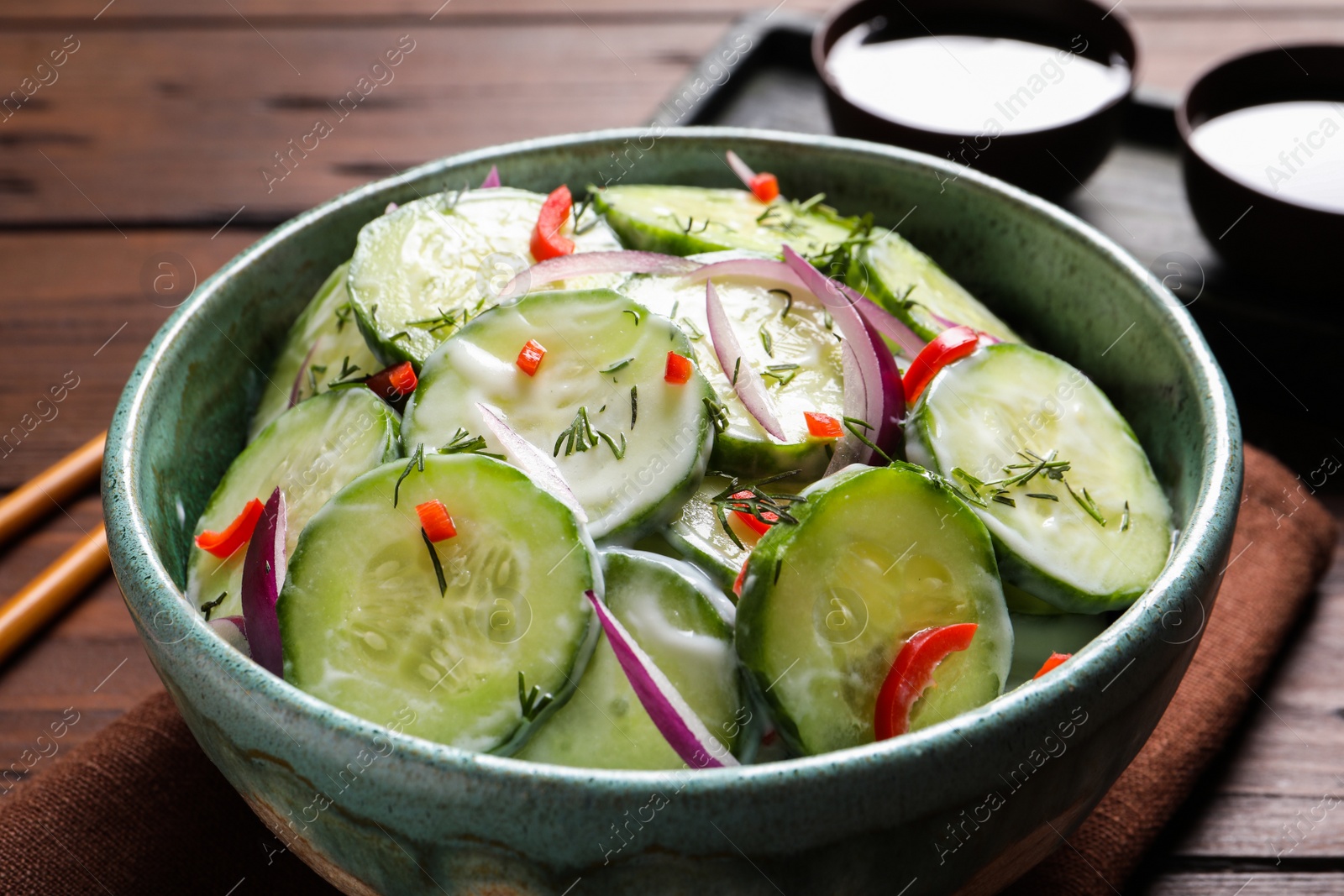 Photo of Dish with fresh creamy cucumber salad on wooden table