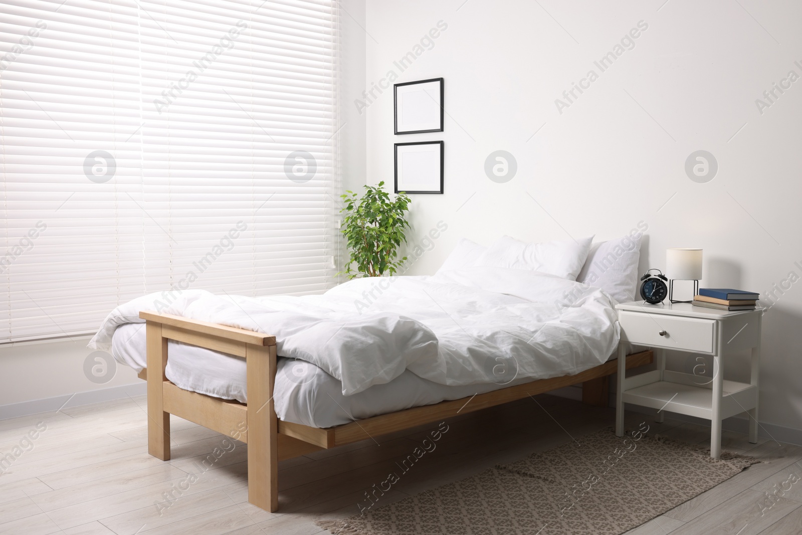 Photo of Stylish light room with comfortable bed and bedside table. Interior design