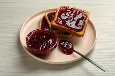 Photo of Delicious toasts with jam served on white wooden table