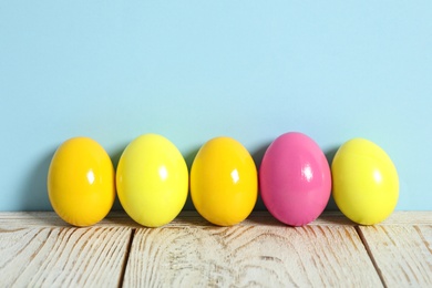 Photo of Easter eggs on white wooden table against light blue background, space for text