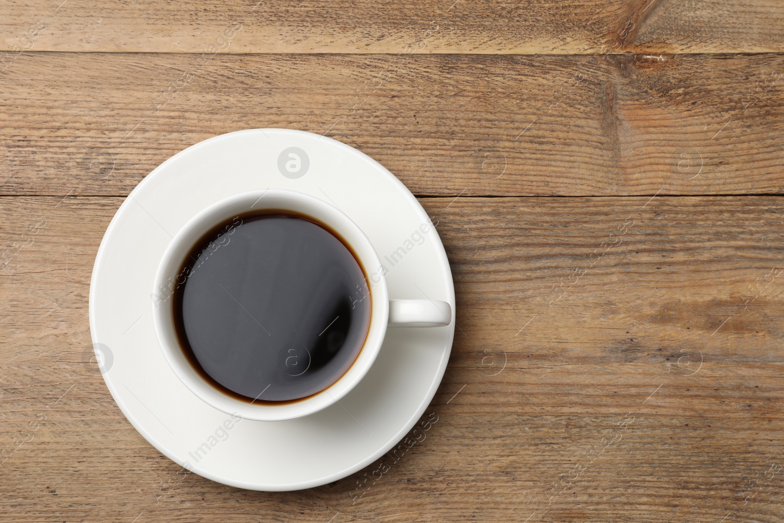 Photo of Cup of aromatic coffee on wooden table, top view. Space for text