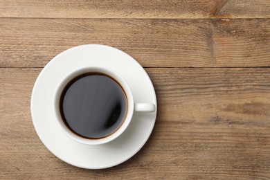 Photo of Cup of aromatic coffee on wooden table, top view. Space for text