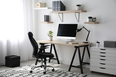 Photo of Comfortable office chair near table with modern computer