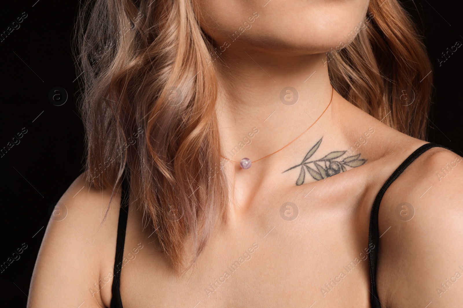 Photo of Beautiful woman with tattoo on body against black background, closeup