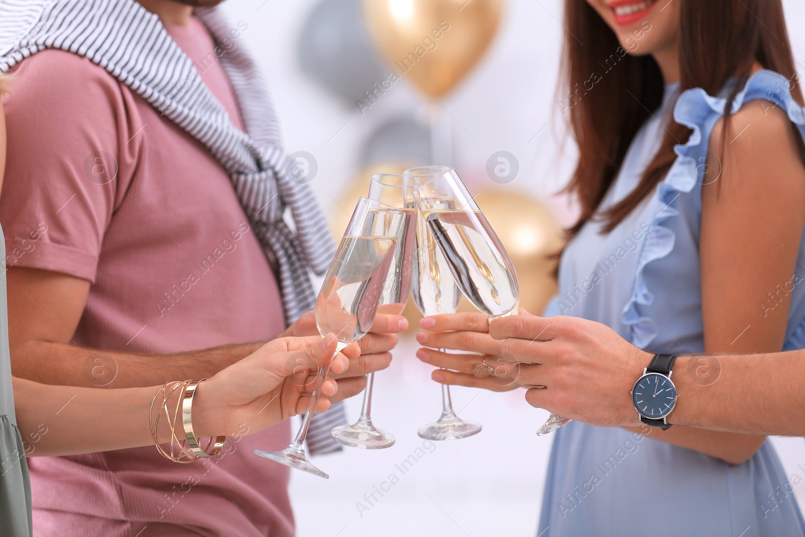 Photo of Friends clinking glasses with champagne on blurred background, closeup