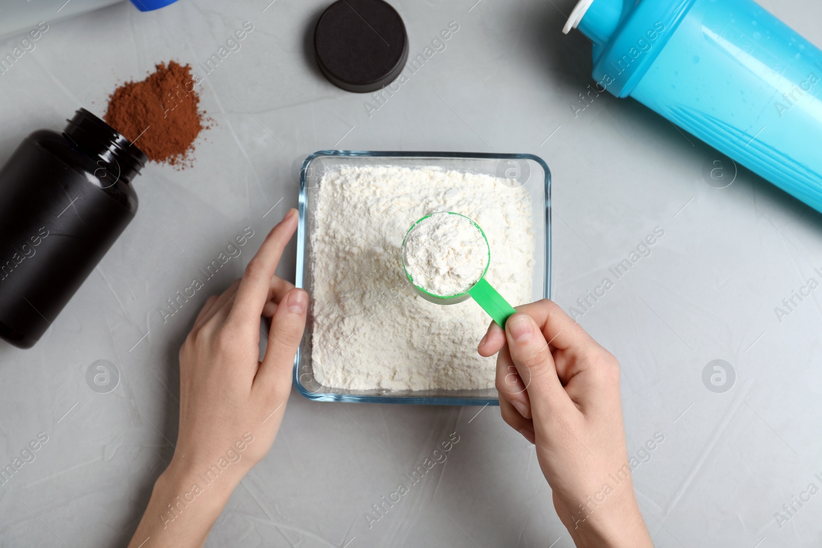 Photo of Man preparing protein shake with powder at grey table, top view