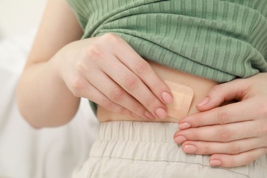 Photo of Woman applying contraceptive patch onto her body, closeup