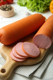 Photo of Board with tasty boiled sausages on white wooden table