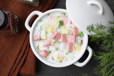 Photo of Delicious cold summer soup (okroshka) with boiled sausage in pot on grey wooden table, top view