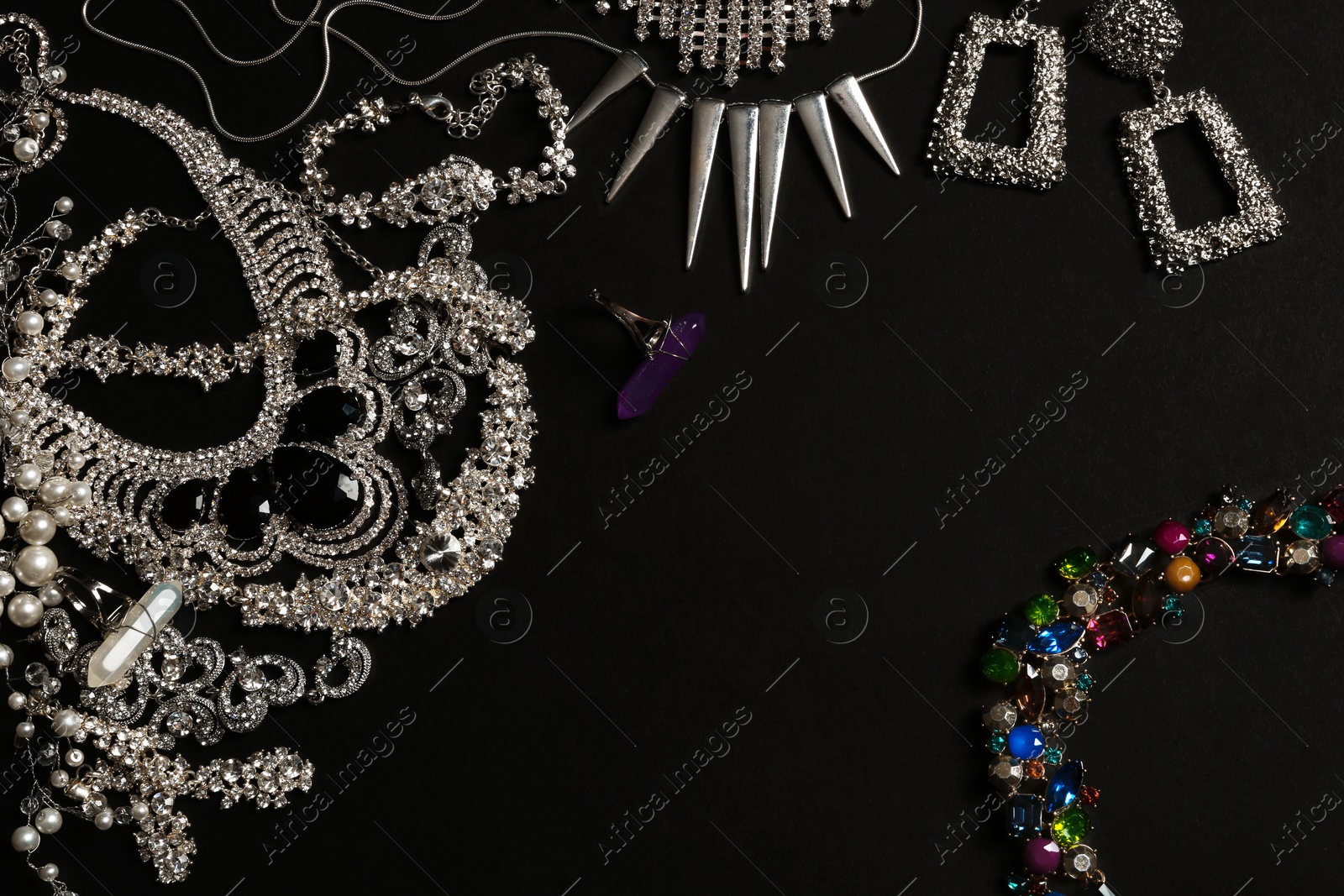 Photo of Frame made of different elegant jewelry on black background, top view. Space for text