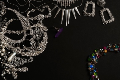 Photo of Frame made of different elegant jewelry on black background, top view. Space for text