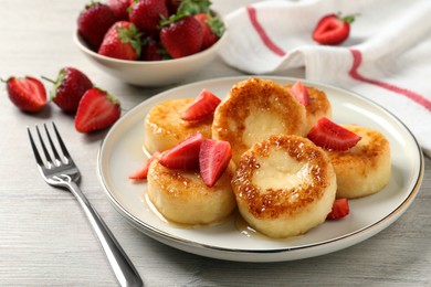 Photo of Delicious cottage cheese pancakes with strawberries and honey on white wooden table
