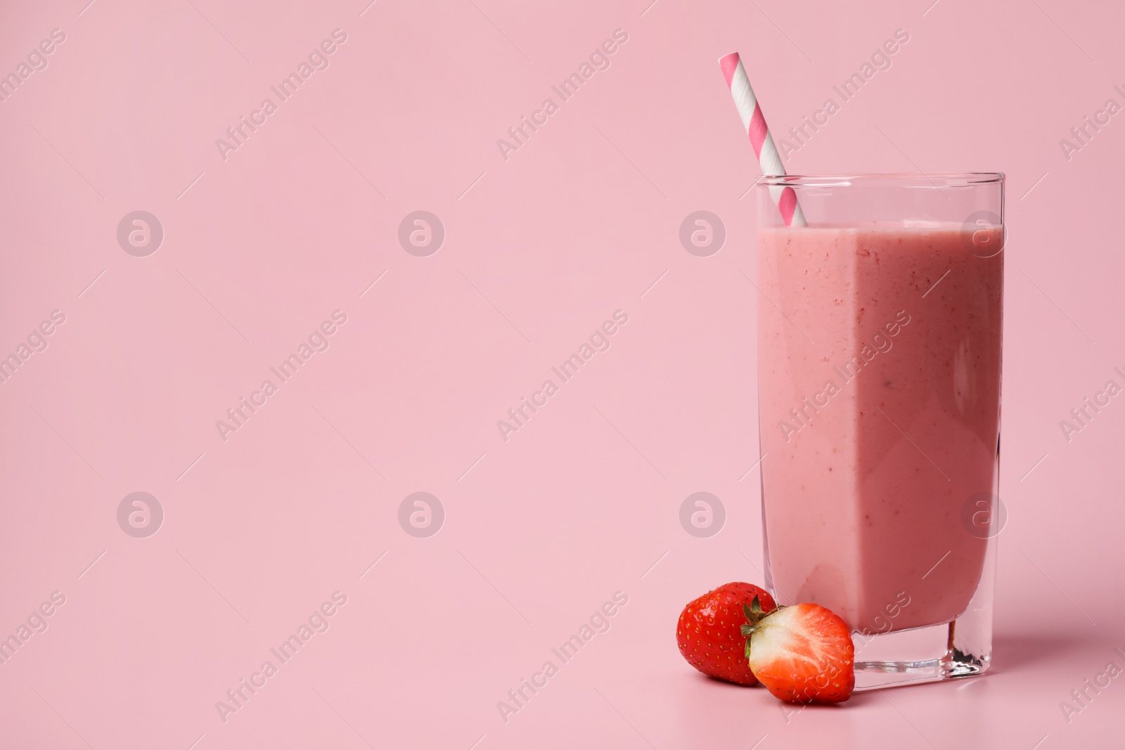 Photo of Glass with delicious berry smoothie and fresh strawberries on pink background. Space for text