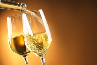 Photo of Pouring tasty aromatic wine in glass on brown background, closeup. Space for text