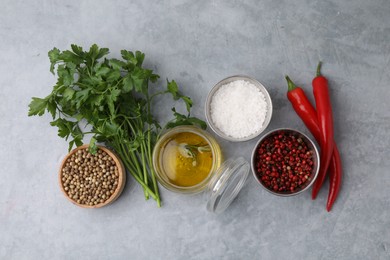 Aromatic peppercorns and different fresh ingredients for marinade on grey table, flat lay