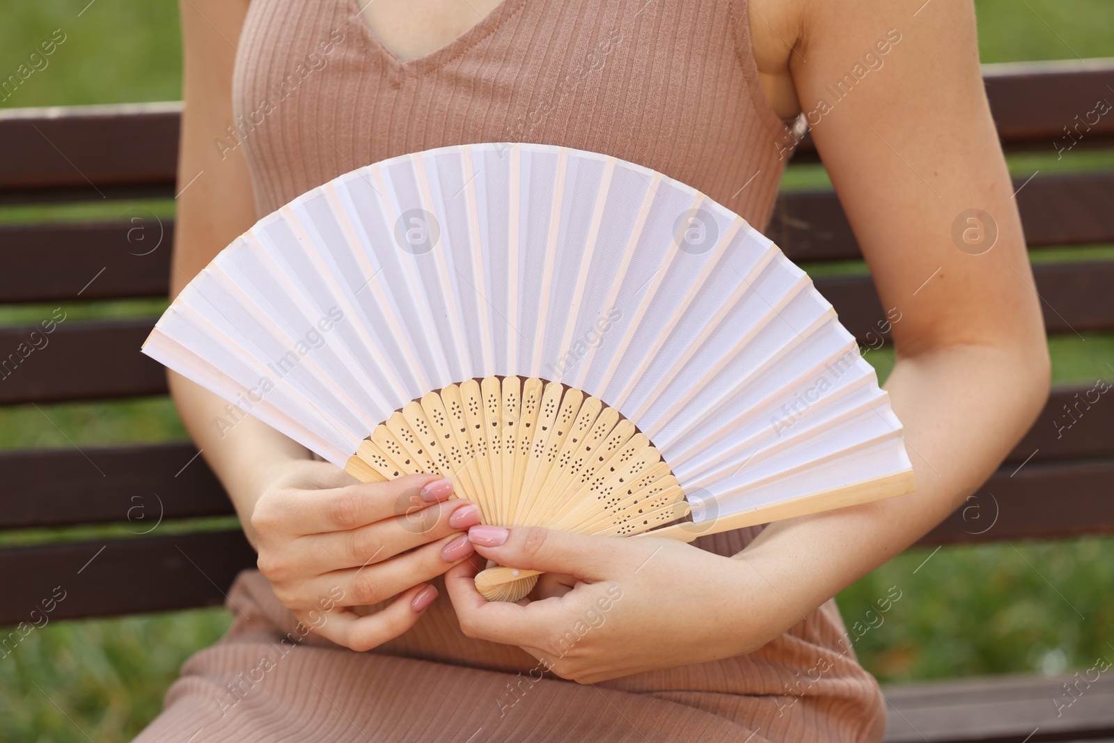 Photo of Woman with white hand fan outdoors, closeup