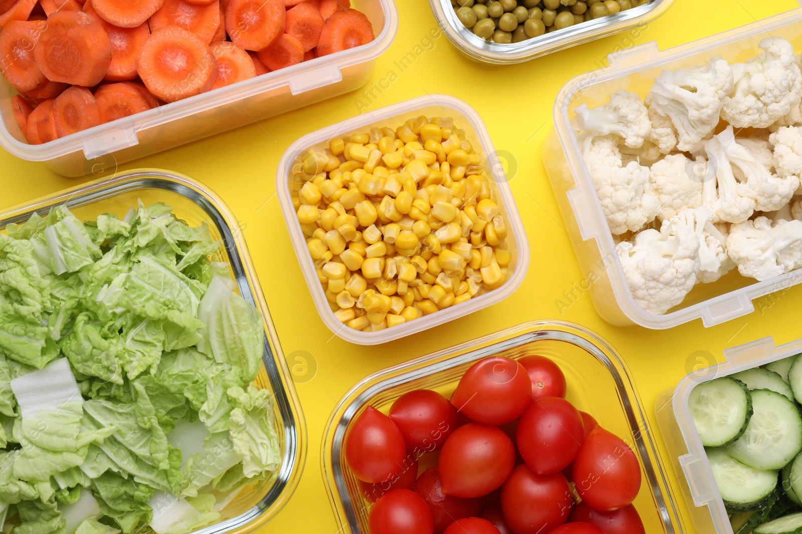 Photo of Plastic and glass containers with different fresh products on yellow background, flat lay