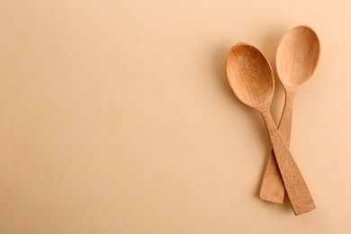 Clean wooden spoons and space for text on color background, flat lay