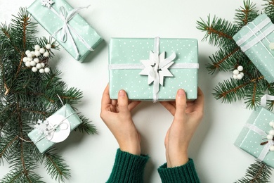 Photo of Woman holding Christmas gift box at white table, top view