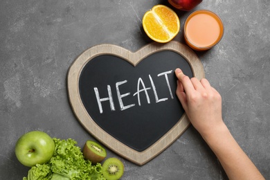 Woman writing word "HEALTH" on blackboard, top view. Concept of weight loss