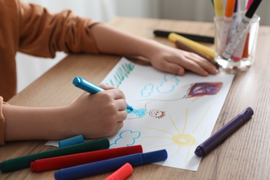 Little girl drawing picture with marker at wooden table, closeup. Child`s art