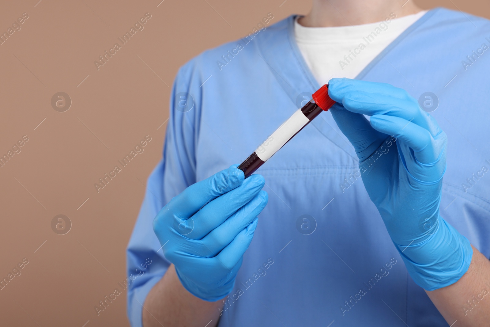 Photo of Laboratory testing. Doctor with blood sample in tube on light brown background, closeup