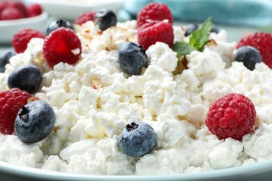 Photo of Delicious cottage cheese with fresh berries on plate, closeup. Tasty breakfast