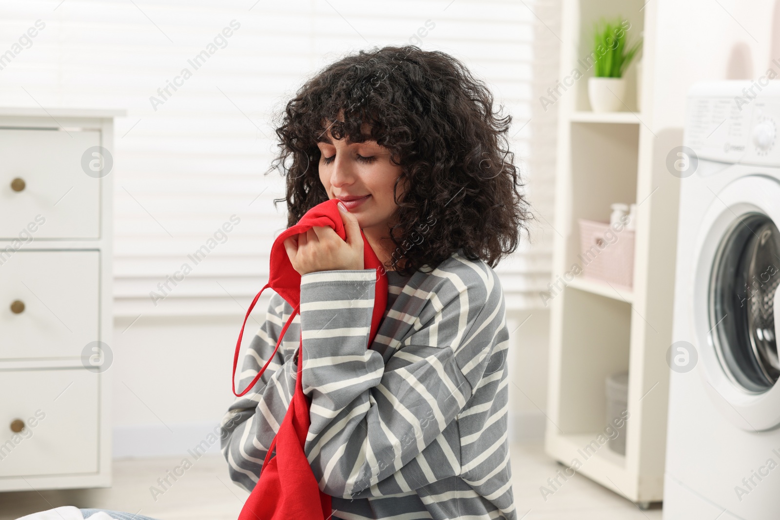 Photo of Beautiful woman with clean laundry at home