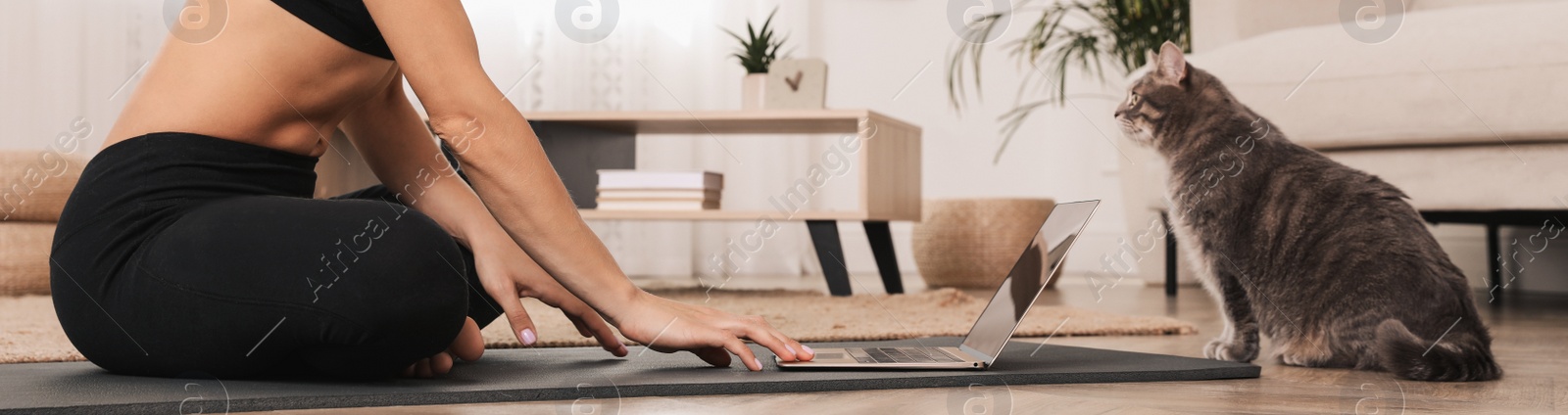 Image of Woman with her cat watching online yoga class at home. Horizontal banner design 