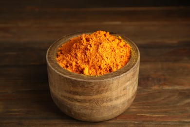 Photo of Aromatic saffron powder in bowl on wooden table