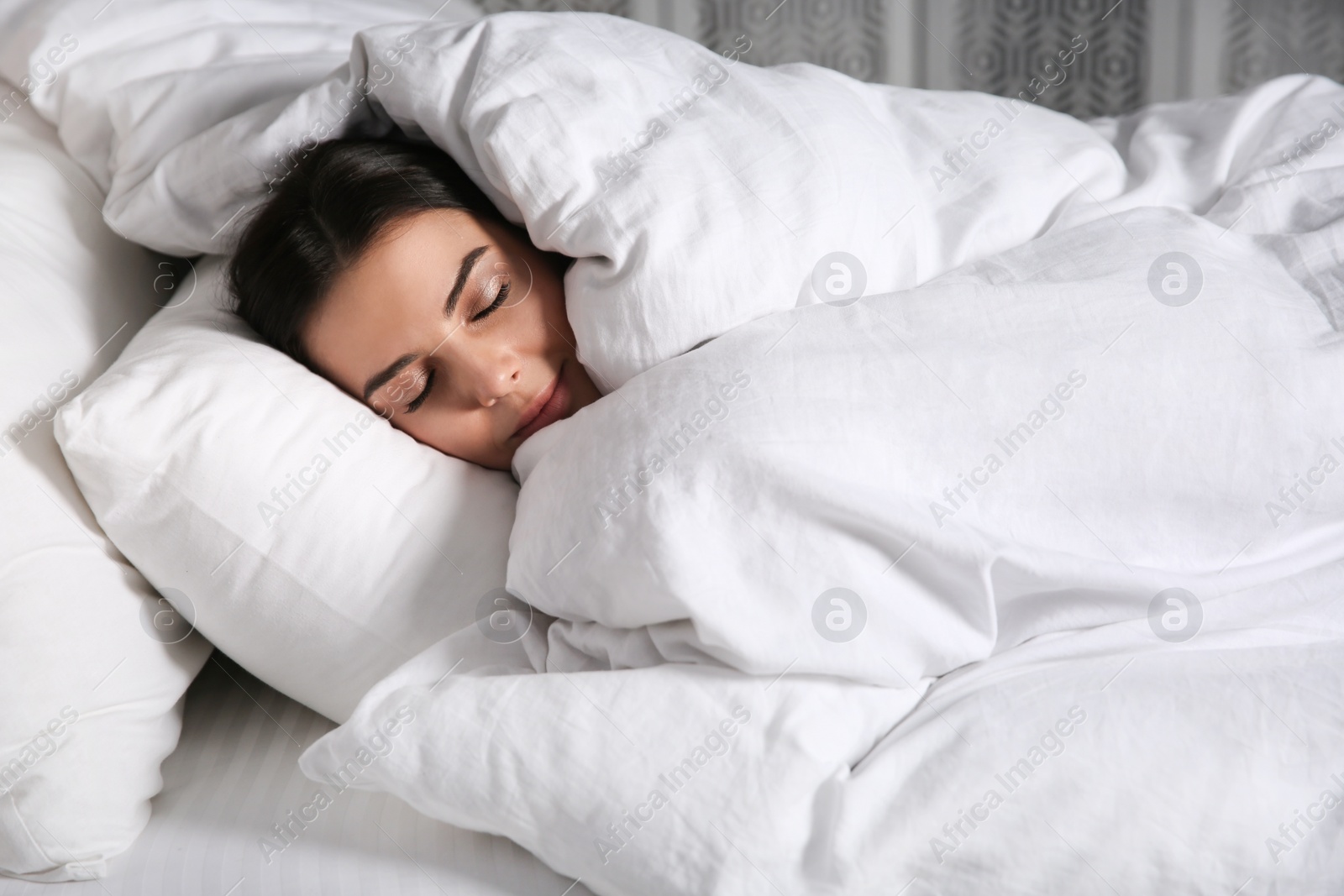 Photo of Young woman sleeping in bed covered with white blanket