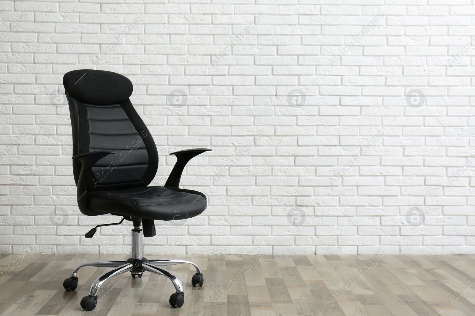 Photo of Comfortable office chair near white brick wall indoors. Space for text