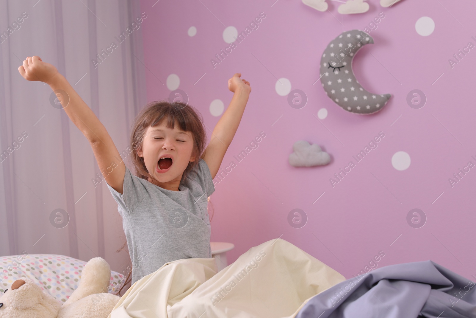 Photo of Little girl stretching in bed at home. Time to sleep