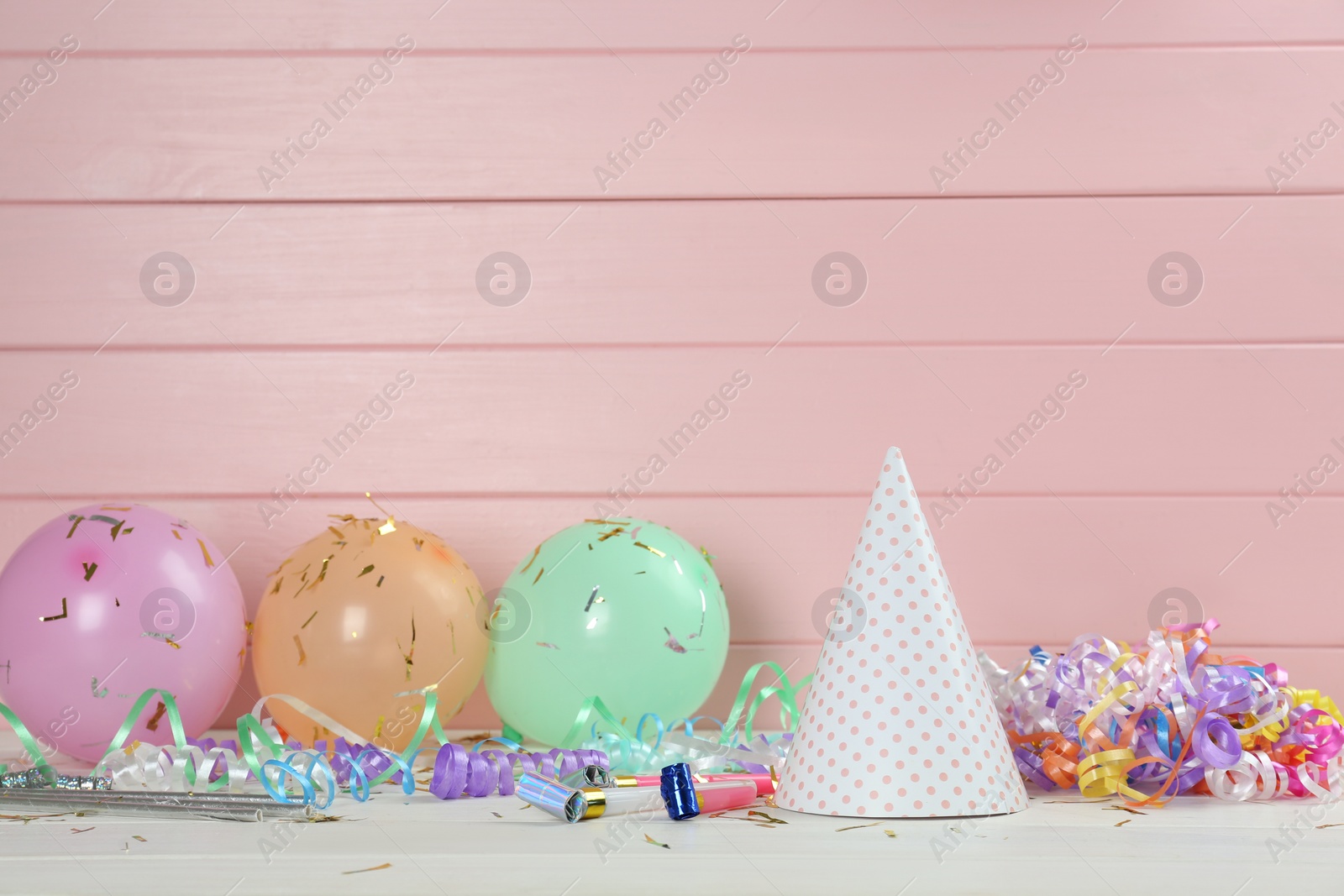 Photo of Colorful serpentine streamers and other party accessories on white wooden table. Space for text