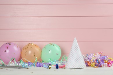 Photo of Colorful serpentine streamers and other party accessories on white wooden table. Space for text