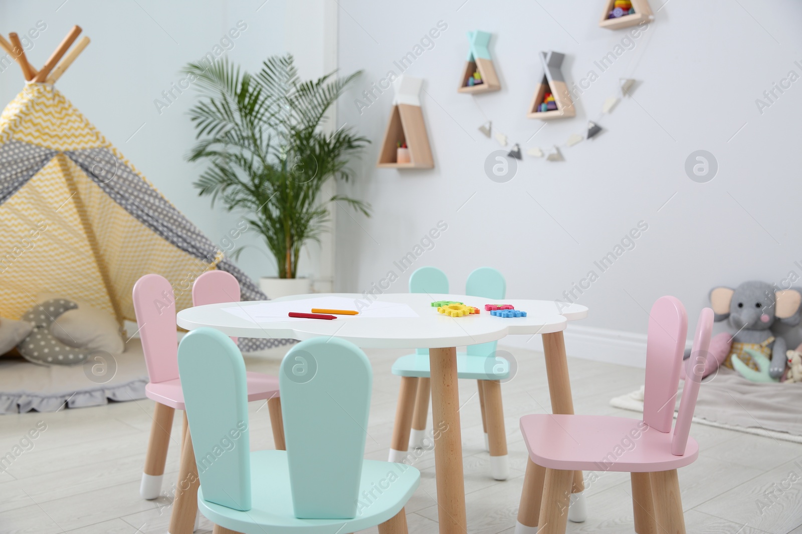 Photo of Little table and chairs with bunny ears in children's room. Interior design