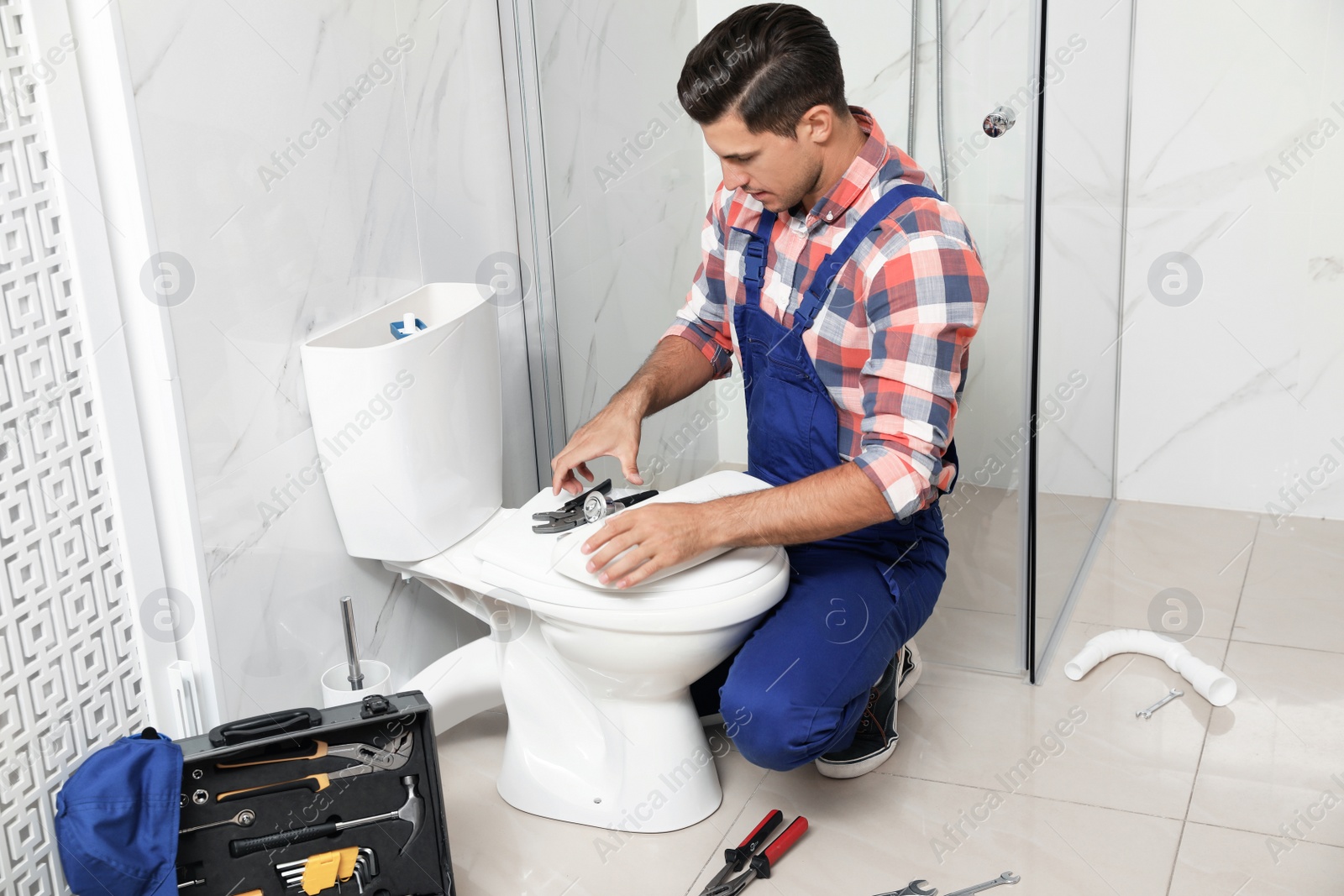 Photo of Professional plumber working with toilet bowl in bathroom