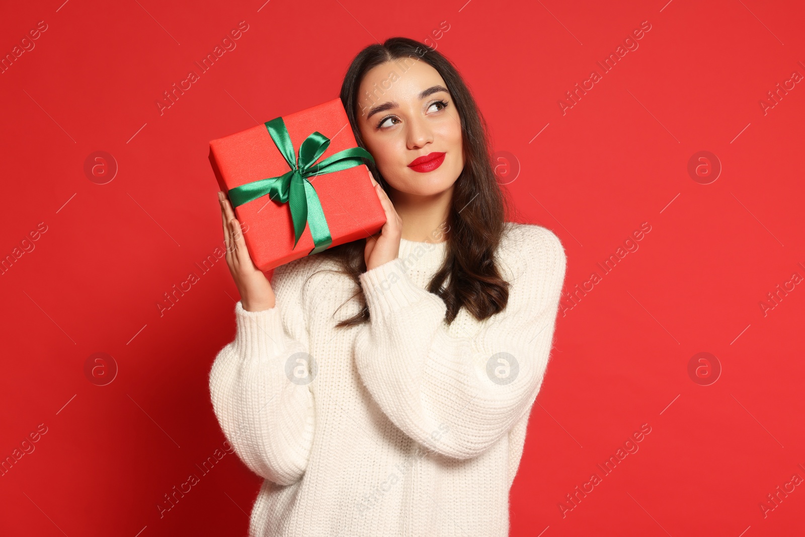 Photo of Beautiful young woman with Christmas gift on red background