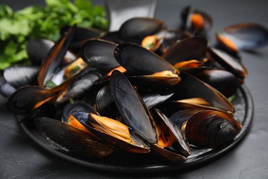 Photo of Serving slate board with cooked mussels on table, closeup