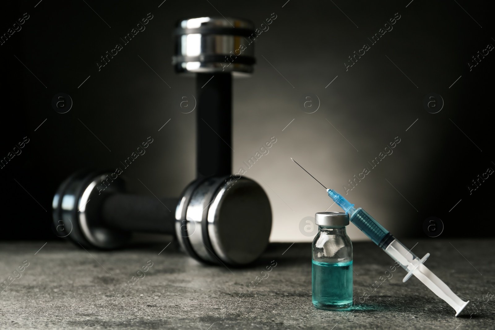 Photo of Vial, syringe with drug near sports equipment on grey table, space for text. Doping control