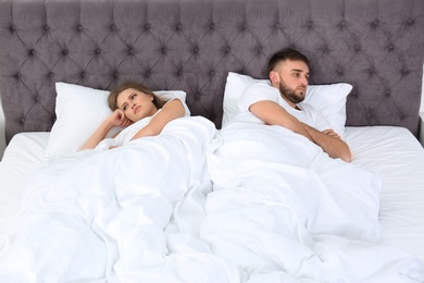 Upset young couple with relationship problems in bedroom