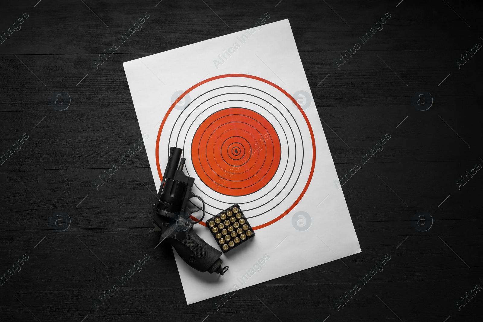 Photo of Shooting target, handgun and bullets on black table, top view