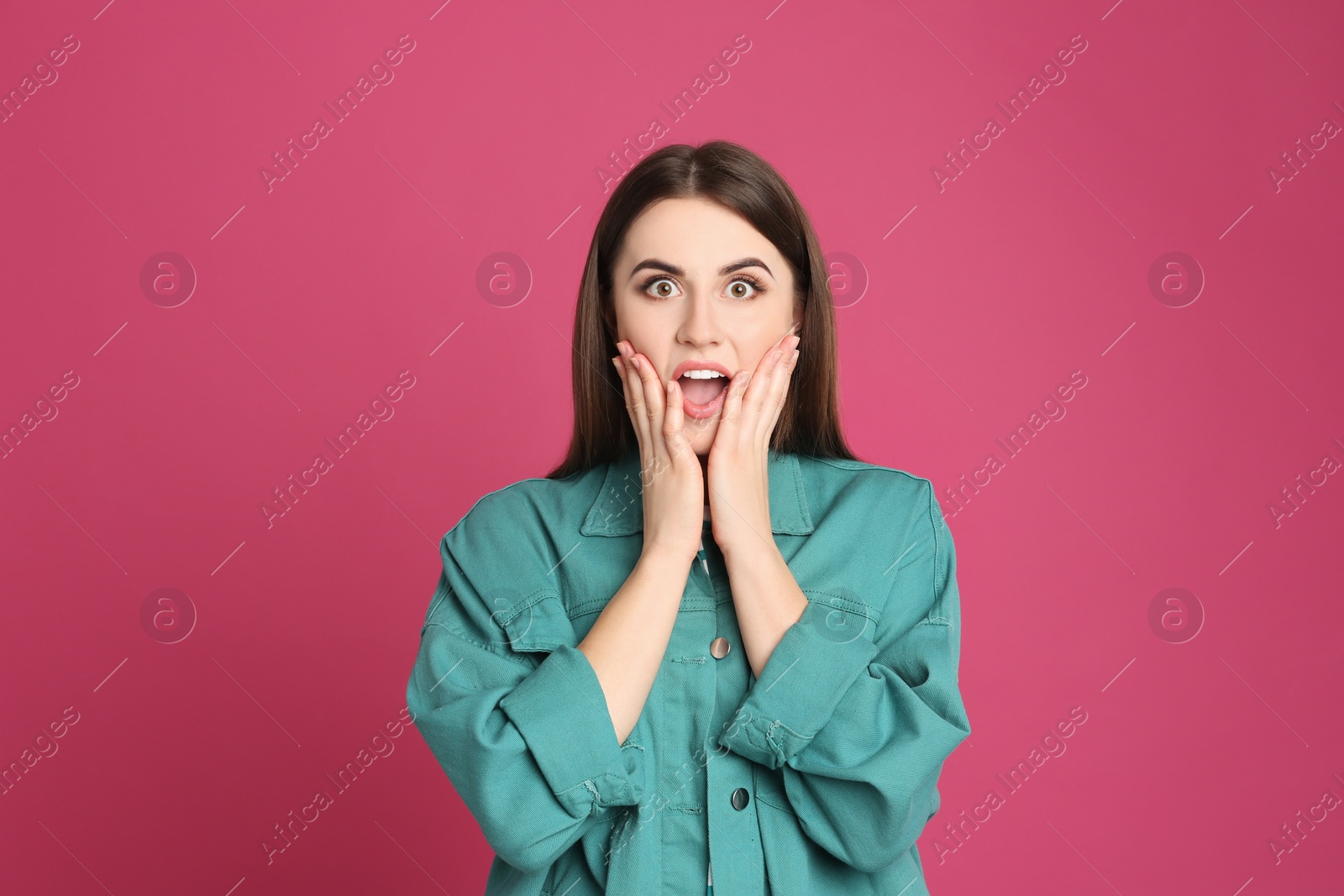 Photo of Portrait of shocked young woman on pink background