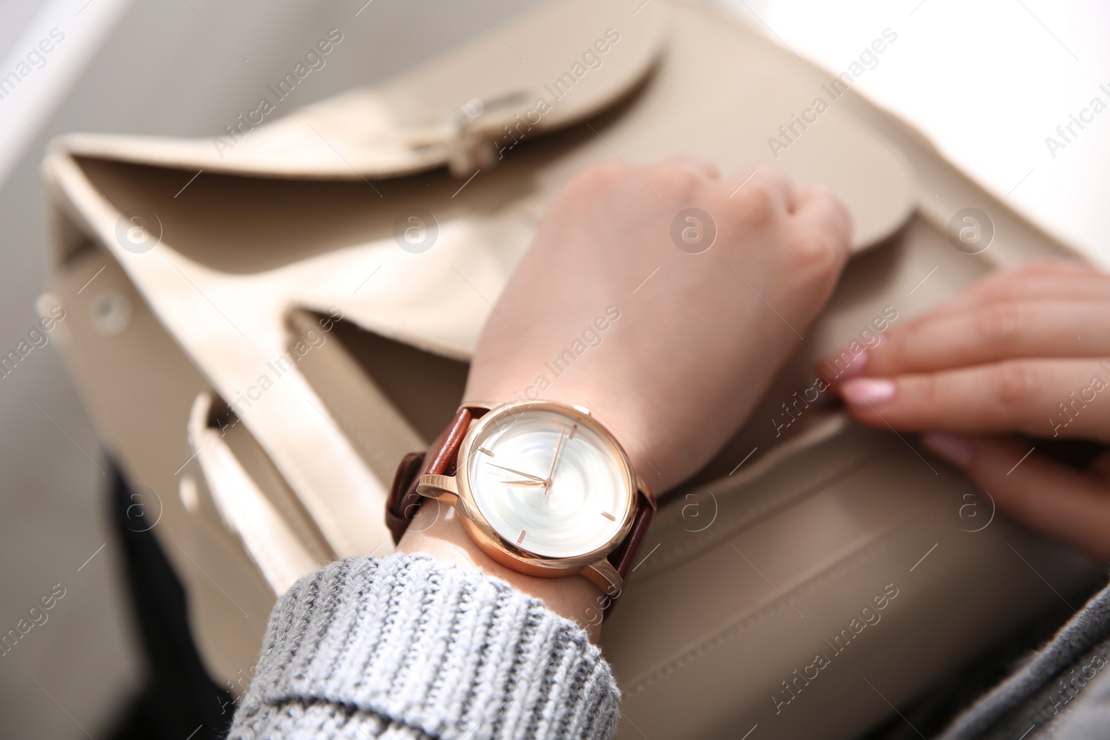 Photo of Woman with luxury wristwatch and handbag on blurred background, closeup