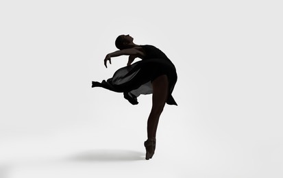 Image of Beautiful ballerina with black veil dancing on light background. Dark silhouette of dancer